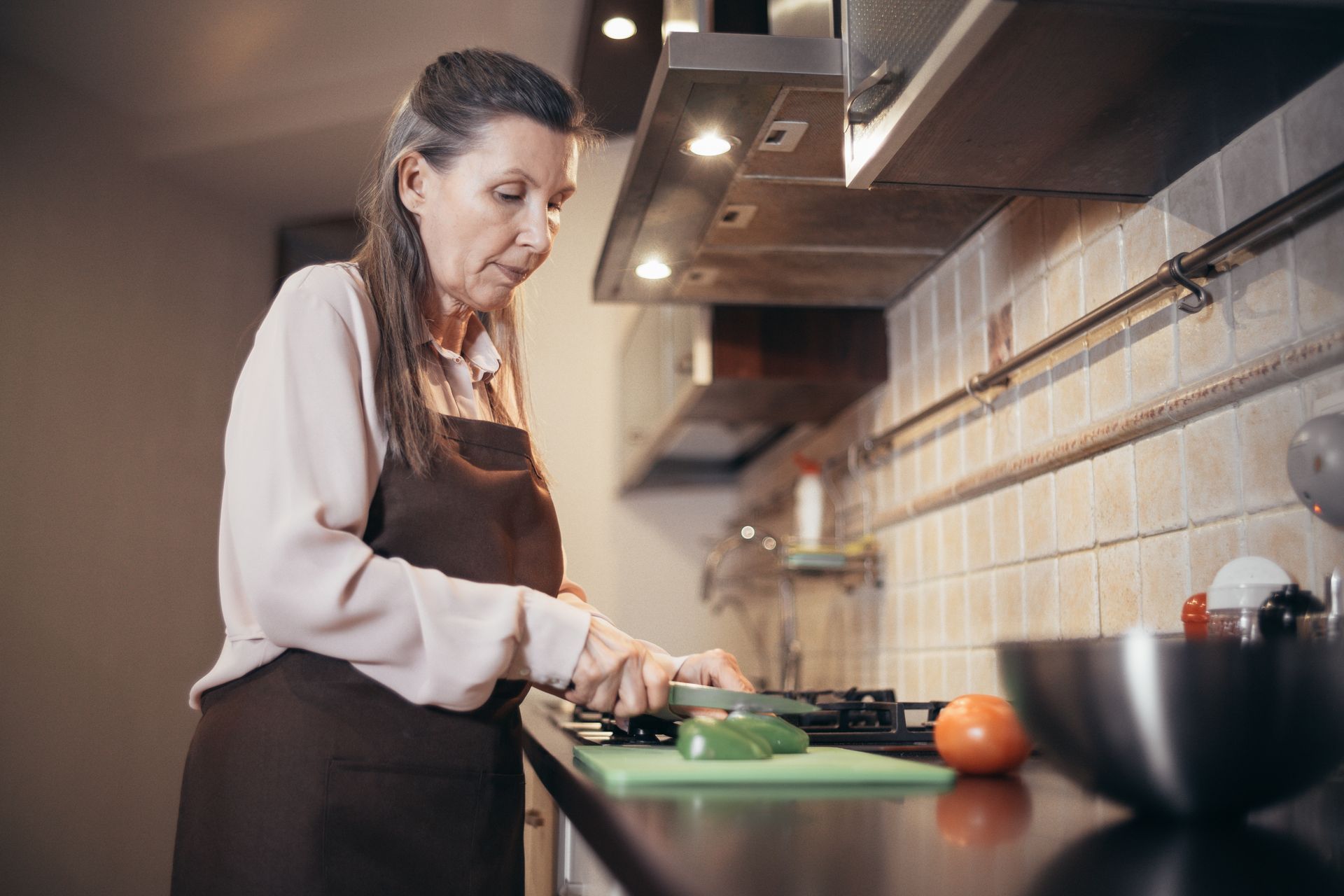 A woman preparing vegetables for a meal in a home kitchen.